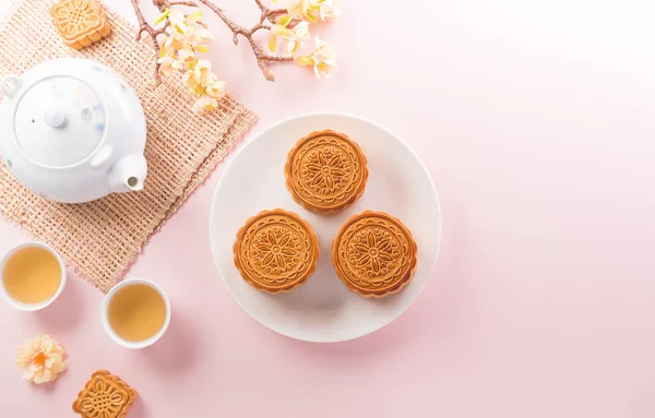 Chinese Mid-Autumn Festival concept made from mooncakes, tea and plum blossom on pastel background.