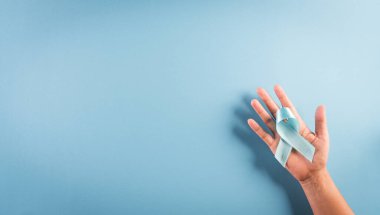 Dünya Diyabet Günü Farkındalık Konsepti. El ele tutuşan mavi kurdele, sembolik yay rengi pastel arka planda diyabet gününde farkındalığı artırıyor, 14 Kasım.