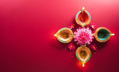 Happy Diwali - Clay Diya lamps lit during Diwali, Hindu festival of lights celebration. Colorful traditional oil lamp diya on red background