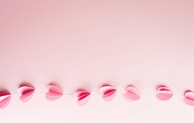 Aşk ve Sevgililer Günü kavramı pastel arka plandaki pembe kağıt kalplerden yapılmıştır..