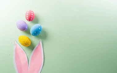 Paskalya partisi konsepti. Paskalya tavşanı kulakları ve pastel arka planda renkli yumurtaların üst görüntüsü metin için telif alanı ile.