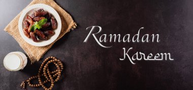 Ramazan Kareem arkaplan kavramı, meyveli, sütlü tespih boncuğu ve koyu taş zemin üzerine yazılmış metin..