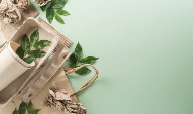 Dünya Çevre Günü, yeşile dönün, geri dönüşüm, toprak günü ve eko konsepti, farklı kağıt atık malzemeleri ve pastel arka planda bitki.