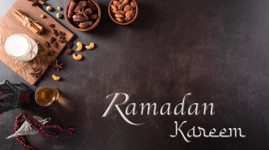 Ramazan Kareem 'in masa üstü resmi, meyve, aladdin lambası, süt ve tespih taneleri koyu taştan arka planda. Kopyalama alanı olan düz.