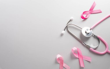 Pink ribbon and stethoscope on paper background for supporting breast cancer awareness month campaign.