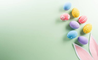 Paskalya partisi konsepti. Paskalya tavşanı kulakları ve pastel arka planda renkli yumurtaların üst görüntüsü metin için telif alanı ile.