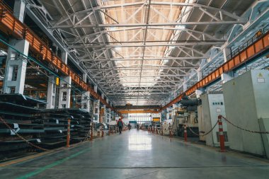 Büyük endüstriyel fabrika içi. İşçiler ve teknik ekipmanlar atölyede.