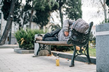 Homeless man sleeping on bench. Poor beggar on city street.