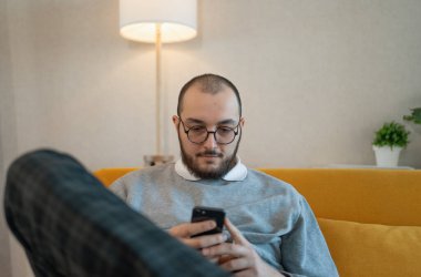 Man using smartphone at home, browsing internet news, social media or downloading application or app.