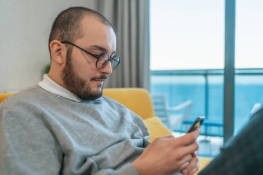 Man using smartphone at home, browsing internet news, social media or downloading application or app.