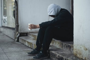 Homeless man sits on steps and asks for help and money.