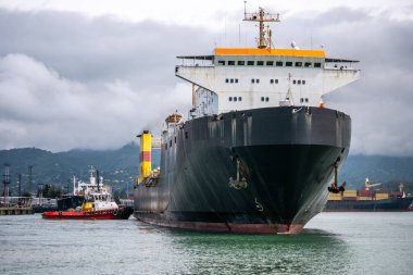 Römorkör limana gelen büyük bir kargo gemisini itiyor. Yük deniz taşımacılığı kavramı.