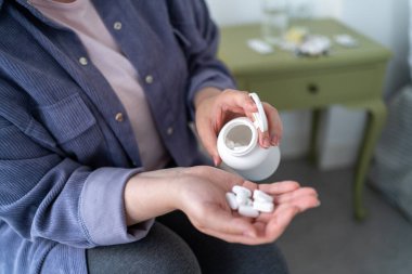 Kadın ilaç şişesinden avucuna beyaz hap ya da ilaç döktü. Ev tedavisi, ilaçlar ve uyuşturucular.