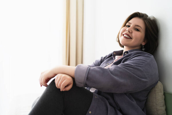 Plus size young woman looks at camera and smile, copy space for text.