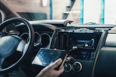 Otomatik elektrikçi ya da araba servisindeki tamirci otomatik panele çoklu ortam ses sistemi ya da araba radyosu yükler.