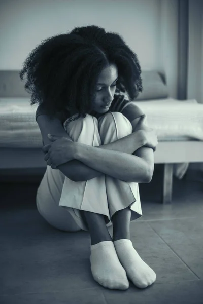 感情的なストレスでかわいい黒人の少女は 自宅の床に一人で座っています 若いティーンエイジャーは学校での問題やいじめを心配していました 黒と白の画像 — ストック写真