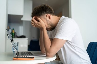 El ele tutuşmuş, bilgisayarla uzaktan kumandalı ofis işi yapan çok çalışan bir adam. Stresli kişi, orta yaş krizi konsepti.