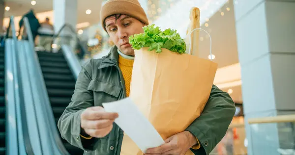 Preiserhöhungskonzept Überraschte Männliche Kundin Mit Papiertüte Mit Lebensmitteln Blickt Nach Stockbild