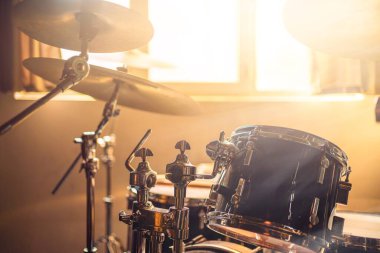 Bateri seti, ahşap ve metalden yapılmış, müzikal bir ortam yaratıyor. Oda sıcak güneş ışığıyla dolu..