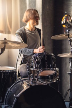 Davulcu, davul başlığı ve zille birlikte müzik stüdyosunda bateri çalıyor..