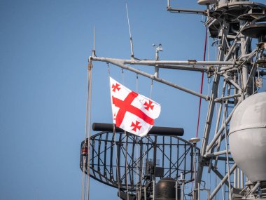 Donanma radar kulesinde dalgalanan Gürcistan bayrağı mavi gökyüzüne karşı karmaşık iletişim ekipmanlarıyla