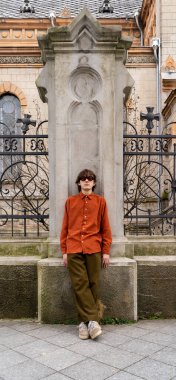 Büyük güneş gözlüklü eski moda bir adam şehir merkezindeki dekoratif tarih binasına kesinlikle karşı duruyor. Modern geçmişe dönük ve nostaljik moda kavramı.