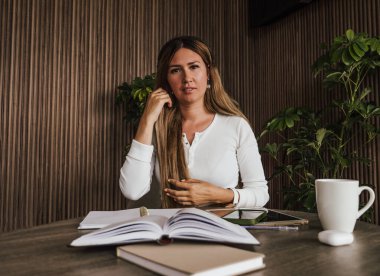 Çalışması sırasında duraklayan düşünceli genç kadın, bir sonraki iş veya eğitim adımlarını yansıtıyor veya planlıyor.