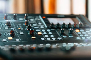 Aydınlatılmış düğmeler ve düğmelerle ses karıştırma konsolu, müzik üretimi ve kaydı için profesyonel ses donanımı. Kayıt stüdyosundaki modern ses arayüzünün yakın görüntüsü.