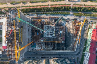 Kentsel alanda birden fazla vinç ve bina yapısına sahip büyük inşaat alanının havadan görünüşü, gelişim süreci.