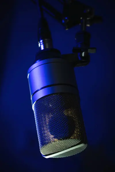 stock image Professional studio microphone illuminated by blue lighting, podcasts and voice recording, vertical close up image