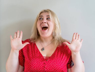 Kırmızı elbiseli neşeli, iri yarı kadın elleri havada gülüyor.. 