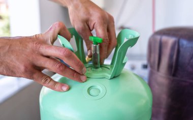 Havalandırma bakımı sırasında soğutucu tankının vanasını ayarlayan teknisyen elleri. Profesyonel HVAC hizmeti ve onarım, uygun soğutma sistemi işlevselliğini sağlama. 