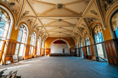 Abandoned Soviet-era sanatorium interior in Tskaltubo, Georgia. Grand hall features large arched windows, ceiling details, and decaying walls, forgotten piece of architectural history. clipart