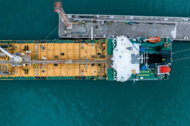 İskeleye yanaşan büyük petrol tankerinin yukarıdan aşağıya havadan çekilmiş görüntüleri, endüstriyel güverte detayları, küresel ticaret ve petrol tedarik zinciri. 