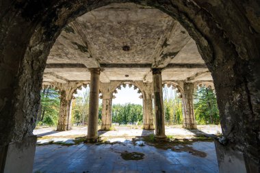 Antik kemer ve sütunlarla çerçevelenmiş, ışık ve gölgeleri harmanlayan harap saray verandası manzarası. Terk edilmiş miras sitesi huzur dolu ama gizemli bir güzellik sunuyor..