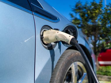 Çevre dostu taşımacılık için elektrikli araba şarj prizi, açık hava park alanında sürdürülebilir hareketlilik eğilimi ve temiz enerji geleceği göstermektedir.