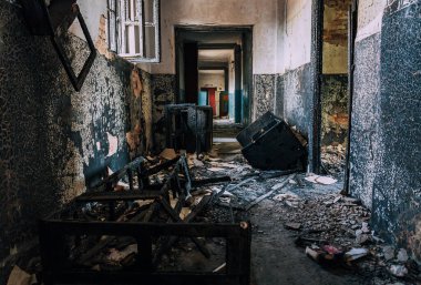Kömürleşmiş molozlar, yanmış duvarlar, kırık pencere çerçeveleri ve yıkılan yangından sonra etrafa saçılmış kalıntılarla dolu terk edilmiş bir koridor..