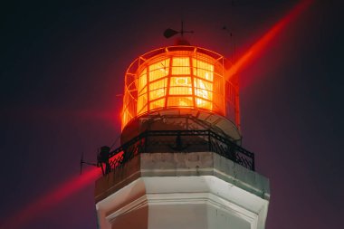 Deniz feneri, gece karanlığında gökyüzüne parlak altın bir ışık saçarak rehberliği, güvenliği ve umudu sembolize ediyor. Seyahat, denizcilik ve ilham verici temalar için büyüleyici bir kompozisyon. 