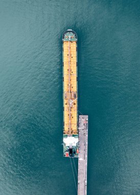 Petrol tankeri iskeleye yanaşıyor, İHA 'nın havadan görünüşü. Deniz lojistiği ve küresel tedarik zinciri, hayati enerji nakli.