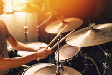 Baterist parlak ev stüdyosunda bateri çalıyor. Güneş ışığı, müzik konsepti, ritim, perküsyon, müzisyen yaşam tarzı ve ses prodüksiyonu..