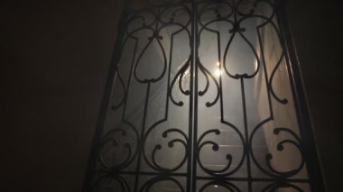 Korku Cadılar Bayramı konsepti. Ürkütücü terk edilmiş kale. Eski bir şamdan ve cadılar bayramı balkabağı tahta merdivenlerde parlıyor ve geceleri kafes kapılı. Arkaplan ışığı ve sisli dekorasyon. Seçici odak
