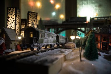 Noel evleri, tren istasyonları, ağaçlarla kaplı kış manzaralarının minyatürü. Gece sahnesi. Eski oyuncak şehrinde yeni yıl. Seçici odak