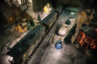 Noel evleri, tren istasyonları, ağaçlarla kaplı kış manzaralarının minyatürü. Gece sahnesi. Eski oyuncak şehrinde yeni yıl. Seçici odak