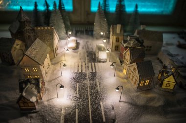 Kışın karlı küçük dekoratif evler, Noel ve yeni yıl minyatür evleri geceleri karlı köknar ağaçları. Tatil konsepti. Seçici odak