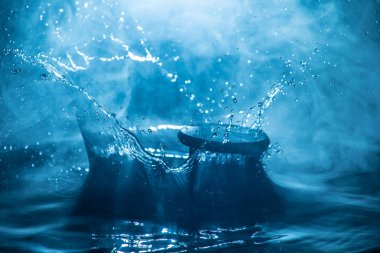 Soyut zaman kavramı. Kum saati suya düştü ya da sisli zemine su sıçrattı. Seçici odak.