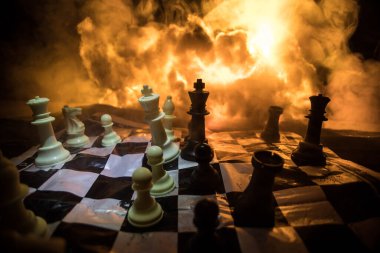 Satranç masası iş fikirleri, rekabet ya da savaş teması konsepti. Patlama ve ateş bulutlarının karanlık arka planında satranç figürleri. Seçici odak