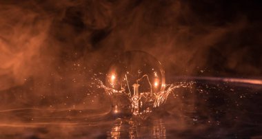 Soyut kavram. Ampulün suya düşmesi ya da sisli zemine su sıçraması. Seçici odak.