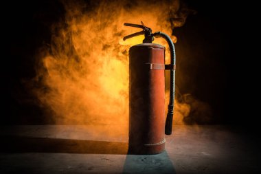 Yangın koruma konsepti. Karanlık sisli arka planda, ışıklı eski bir yangın söndürücü. Seçici odak
