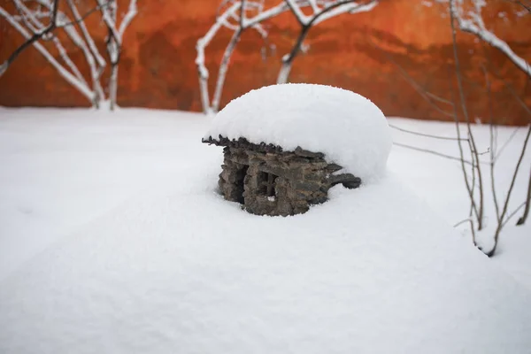 a little stone house covered with snow at the garden during wintertime. Decorative little house.