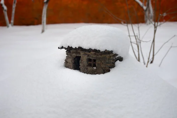 a little stone house covered with snow at the garden during wintertime. Decorative little house.